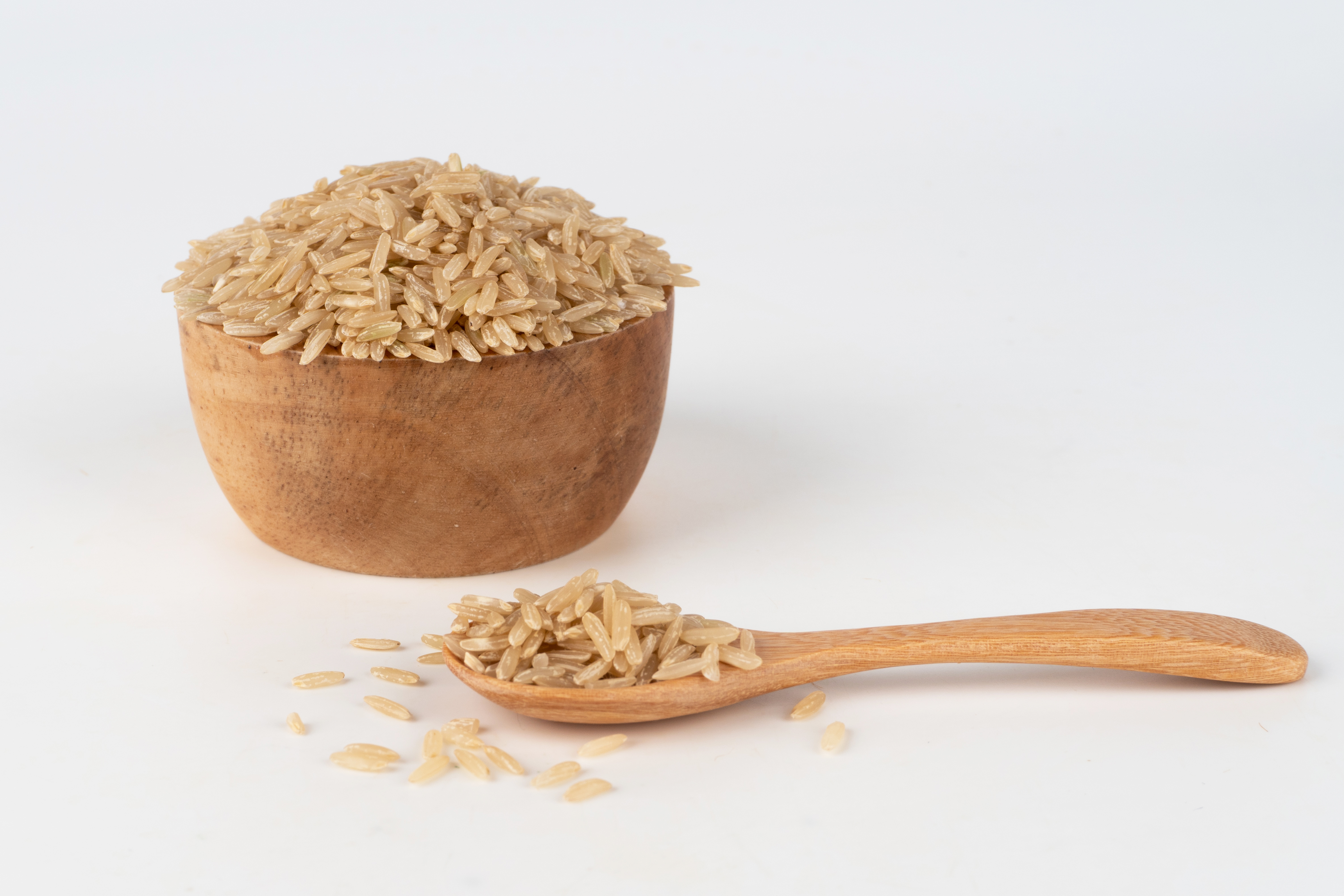 brown-rice-wooden-bowl-spoon-overflowing-out-scattered-floor